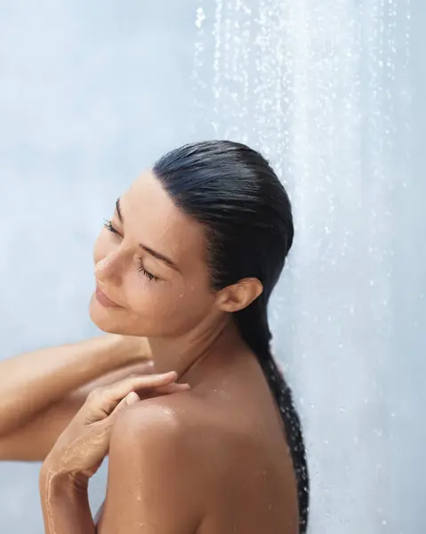 Stock image A peaceful woman with her eyes closed relishes a refreshing shower, embracing a tranquil moment of rejuvenation. Perfect for themes related to beauty, relaxation, and wellness. 