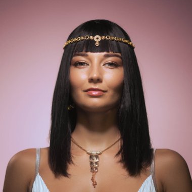 Kleopatra gibi giyinmiş çarpıcı bir kadın portresi detaylı makyaj, karmaşık mücevherler ve geleneksel bir saç stili sergiliyor. Tarihi temalar, moda yazıları ve karakter için mükemmel.