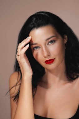 Kırmızı dudaklı güzel bir kadın zarifçe poz veriyor zarafetini ve inceliğini sergiliyor. Lüks güzellik tedavileri, kozmetik ürünleri, cilt bakımı ve kaliteli güzellik kaplıcaları için mükemmel..