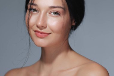 Doğal makyajlı ve çıplak omuzlu güzel bir genç kadının yakın plan portresi. Reklamlarda ve reklamlarda güzellik, cilt bakımı ve kozmetik kavramları için ideal.. 