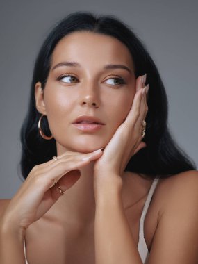 Parlak tenli ve zarif hatları olan zarif bir kadının stüdyo fotoğrafı. Makyajı ve şık görünüşü bu güzel portreyi moda ve cilt bakımı için ideal kılıyor.