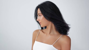 Koyu renk, rüzgarlı saçları olan, pürüzsüz cildini ön plana çıkaran göz kamaştırıcı bir Japon kadın. Saç bakımı ve cilt bakımı için mükemmel. Stüdyo ortamında doğal güzellik ve zarafet gösteriliyor..