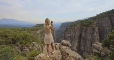 Türkiye 'nin Tazi Kanyonu' ndaki nefes kesici manzarayı telefonuyla çeken bir kadın. Seyahat, doğa ve macera teması için mükemmel. Mekanın güzelliğini ve heyecanını vurgulamak için.. 