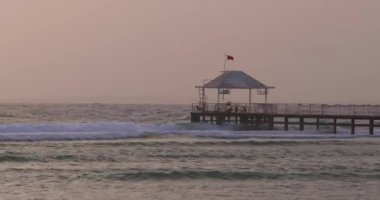 Gün batımında Sharm El Sheikh tatil köyünde Kızıl Deniz 'e uzanan bir iskelenin sakin bir görüntüsü. Seyahat, turizm ve rahatlama temaları için mükemmel. Promosyon kullanımı için yüksek kaliteli görüntüler. 