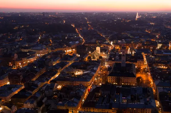Alacakaranlıkta Lviv şehrinin güzel hava manzarası aydınlanmış sokakları ve tarihi binaları aydınlatıyor. Seyahat promosyonları, şehir manzarası fotoğrafçılığı ve şehir macera temaları için mükemmel.