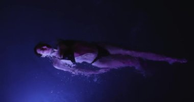 Sakin, genç bir kadın geceleri yüzme havuzunda dinleniyor, yukarıdan manzara seyrediyor. Yüksek kalite ağır çekim 4k görüntü.