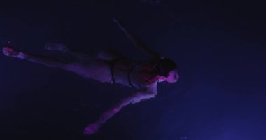 Sakin, genç bir kadın geceleri yüzme havuzunda dinleniyor, yukarıdan manzara seyrediyor. Yüksek kalite ağır çekim 4k görüntü. 