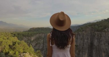 Beyaz elbiseli ve şapkalı bir turist uçurumun kenarında bir vadide dikiliyor. Amazing Tazi Canyon, Bilgelik Vadisi, Manavgat, Antalya, Türkiye. Greyhound Kanyonu, Bilgelik Vadisi
