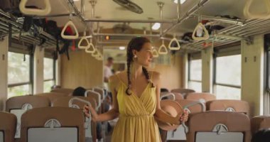 Sarı elbiseli bir kadın Sri Lanka 'da bir tren vagonunda duruyor, seyahat ve maceranın özünü yakalıyor. Bu resim trenin içini ve yeni keşiflerin neşesini vurgular.