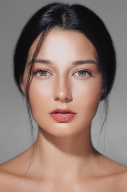 Kusursuz ciltli, doğal makyajlı, koyu renk saçlı, güzelliği ve zarafeti vurgulayan çarpıcı bir kadın portresi. Güzellik tanıtımları, cilt bakımı reklamları ya da makyaj kampanyaları için mükemmel..