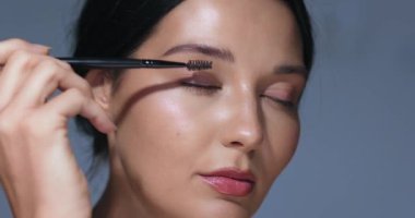 Kirpiklerini fırçayla tarayan, doğal makyajını ve parlak cildini ön plana çıkaran Asyalı bir kadının detaylı görüntüleri. Güzellik, cilt bakımı ve kozmetik promosyonları için ideal.. 