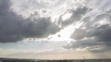 Hızla ilerleyen bulutlar, uzak bir şehrin silueti üzerinde gün ışığından alacakaranlığa dönüşüyor. Havayla ilgili videolar, kentsel manzaralar veya atmosferik kavramsal tanıtımlar için ideal.