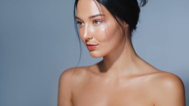 Mavi arka planda, parlak ve nemli bir cilde sahip bir kadının portresi. Güzellik, cilt bakımı, kozmetik reklamları ve yüksek kaliteli konsept promosyonlar için mükemmel..