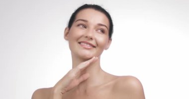 Kusursuz, pırıl pırıl cildi olan zarif bir kadın zarif bir şekilde gülümseyip doğal güzelliği ve sağlığını ön plana çıkarıyor. Spa tedavileri, lüks cilt ürünleri ve güzellik reklamları için ideal