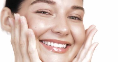 Yüzüne nazikçe sarılan, parıldayan, ışıl ışıl derisini gösteren gülümseyen bir kadının canlı yakın çekimi. Cilt bakımı, güzellik veya sağlık reklamları için ideal. Doğal güzellik ve kendine özen..