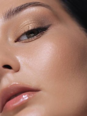 Kusursuz, pürüzsüz ciltli ve doğal makyajlı, gözlerine ve dudaklarına odaklanmış bir kadının yakın çekimi. Güzellik, cilt bakımı ve kozmetik ürün reklamları için mükemmel..