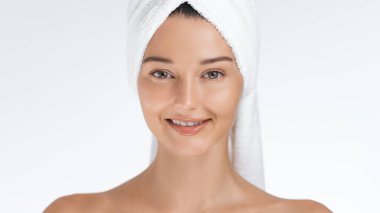 Havluya sarılmış genç bir kadın cilt bakımı rutininden sonra ışıl ışıl gülümser. Tazelik ve sağlıklı bir ten yayar. Güzellik, cilt bakımı, sağlık ve spa tedavileri için mükemmel.