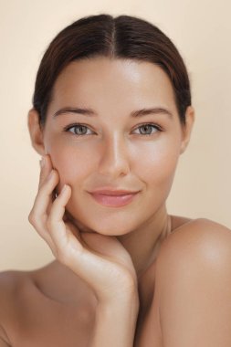Yüzüne nazikçe dokunan, kusursuz bir ten rengine sahip, parıldayan bir kadının portresi. Güzellik, cilt bakımı ve spa ile ilgili kavramlar, nemlendiriciler, makyaj ve yüz bakımı için ideal