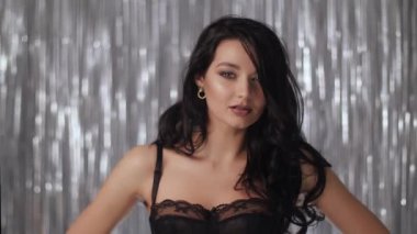 Siyah iç çamaşırlı romantik bir kutlama kadını. Güzel esmer kız portresi, mükemmel bir akşam makyajı ve ışıl ışıl saçlarıyla. Yavaş çekim 4k görüntü