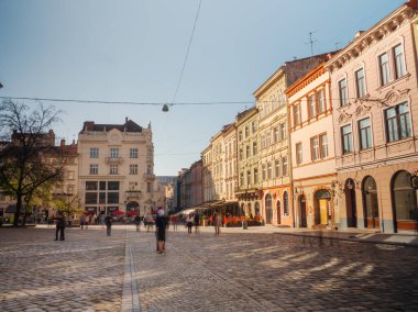 Ukrayna, Lviv 'deki merkez meydanın güzel manzarası, tarihi binalar ve yayalar güneşli bir günün keyfini çıkarıyorlar. Seyahat promosyonları, şehir fotoğrafçılığı ve kültürel keşifler için mükemmel.
