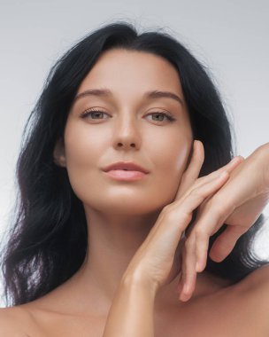 Uzun siyah saçları ve pürüzsüz derisi olan zarif bir Asyalı kadının yakın çekimi. Elleri yüzünün yanında zarifçe poz veriyor. Yaşlanma karşıtı cilt bakımı ürünleri, el kremi ve güzellik için ideal.