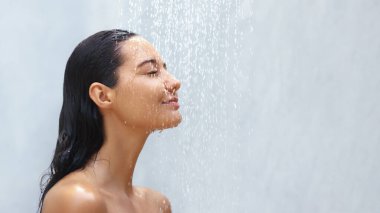 Huzurlu bir kadın hafif bir duşun altında duruyor, gözleri ıslak saçlarının üzerinde çağlayan sular gibi kapalı. Bu görüntü, saf rahatlama anını yakalar ve cilt bakımını, sağlığını ve...