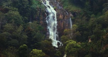 Kuda Ravana Ella şelalesinin Sri Lanka 'daki yoğun yeşil ormanın ortasındaki kayalık kayalıklardan aşağı akışını gösteren görüntüler. Doğanın huzurlu güzelliğini yakalar, seyahat ve macera için idealdir..