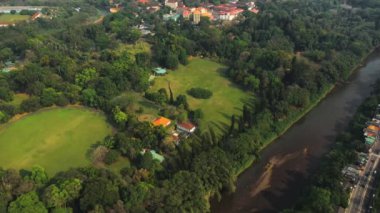 Kandy, Sri Lanka yakınlarındaki Bereketli Peradeniya Kraliyet Botanik Bahçesi 'nin hava görüntüleri yayılan yeşillik ve sakin nehir manzaraları sergiliyor. Doğa, turizm ve seyahat içeriği için ideal.