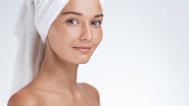 Kafasına havlu sarılmış dingin bir kadın, cilt bakımı sırasında ferahlık saçarak sakince bakar. Güzelliği, kendine bakımı, sağlığı ve cilt bakımını desteklemek için idealdir.