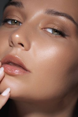 Işıl ışıl, pürüzsüz bir teni ve yumuşak doğal makyajı olan sağlıklı tenini sergileyen bir kadının yakın çekimi. Doğal güzelliği vurgulayan cilt bakımı, güzellik ve kozmetik promosyonları için idealdir.