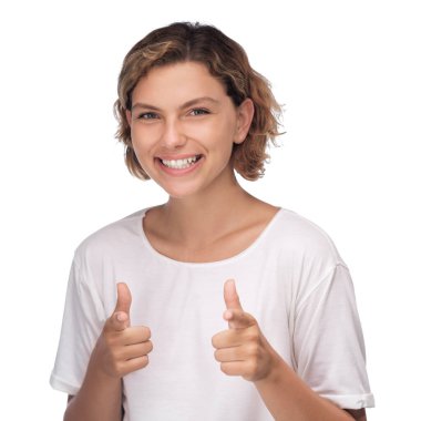 Neşeli bir kadın, beyaz bir arkaplan karşısında kocaman bir gülümsemeyle iki kez onay verir. Bu yüksek kaliteli stok fotoğrafı onay, pozitiflik ve yaşam tarzında teşvik için idealdir.