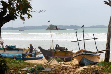 Geleneksel balıkçı tekneleri Weligama, Sri Lanka 'daki kumlu sahil boyunca okyanus ve arka planda küçük bir adayla otururlar. Seyahat, kültür ve yaşam tarzı kampanyaları için ideal