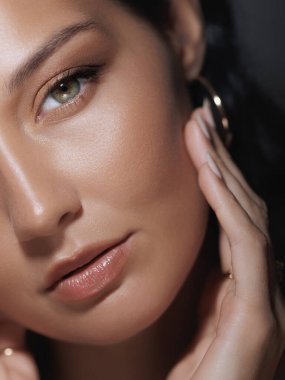 Doğal makyajlı bir kadının yakın çekimi, yüzüne nazikçe dokunmak, parlak cildini ve yumuşak özelliklerini vurgulamak. Güzellik, cilt bakımı ve kozmetik ürünler için mükemmel.
