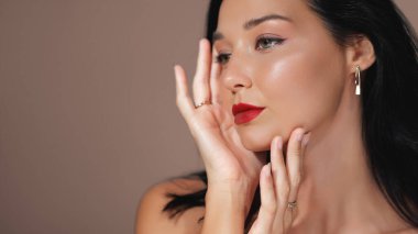 Çekici yeşil gözleri, kırmızı dudakları ve lüks mücevherleri olan bir kadının zarif portresi. Güzellik, moda ve mücevher promosyonları, yüksek kaliteli reklamlar ve editoryal kullanım için ideal.