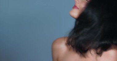 İpek gibi, parlak siyah saçları ve parlak cildi olan güzel bir kadın stüdyo ortamında sağlıklı saçlarını sergilerken kendinden emin bir şekilde gülümsüyor. Saç bakım reklamları, güzellik kampanyaları ve kozmetik ürünleri için mükemmel.
