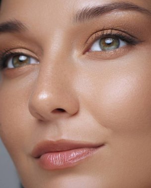 Yeşil gözleri, doğal makyajı ve parlayan derisi olan bir kadının detaylı yakın plan görüntüsü. Cilt bakımı reklamları, kozmetik reklamları ve güzellik ürünleri kampanyaları için mükemmel.. 