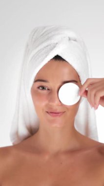 Havlu türbanlı mutlu bir kadın gözüne pamuk tutuyordu. Taze ve parlak bir ten yayıyordu. Cilt bakımı, kişisel bakım ya da güzellik ürünleri promosyonları için mükemmel.. 