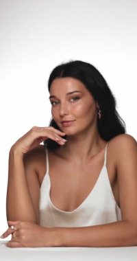 Kusursuz derisi olan zarif bir kadın güzellik portresinde poz verirken nazikçe çenesine dokunuyor. Cilt bakımı kampanyaları, kozmetik promosyonlar ve doğal reklamları vurgulayan güzellik reklamları için ideal.