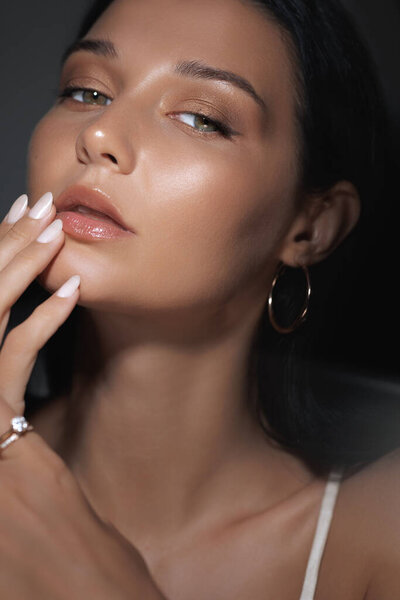 A closeup portrait of a woman with flawless, glowing skin and soft natural makeup, gently touching her face. Ideal for skincare, beauty, and cosmetics promotions highlighting healthy, radiant skin.
