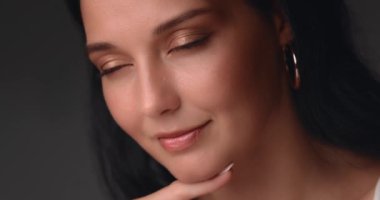 Kusursuz derisi ve yumuşak makyajı olan güzel bir kadının yakın çekimi. Yüzü kısmen yansıtıcı ışıkla aydınlanmış. Güzellik, cilt bakımı veya kozmetik ürün reklamları ve yaşam tarzı için ideal