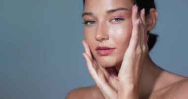 Parlak cildi ve doğal makyajı olan kendine güvenen bir kadın yüzüne nazikçe dokunuyor ve kusursuz bir ten gösteriyor. Cilt bakımı kampanyaları, güzellik reklamları ve kozmetik reklamları için mükemmel.. 