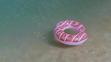 Eğlenceli ve hayat dolu bir yaz sahnesinde bir kadın suya atlıyor, pembe donut şeklindeki şişirilebilir ama neşeli bir şekilde kaçırmayı hedefliyor. Tatil ve macera görselleri için ideal. 