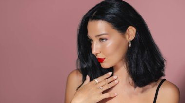 Kırmızı rujlu, parlak tenli ve pembe arka planda poz veren zarif Asyalı kadın. Güzellik, moda ve kozmetik promosyonları için mükemmel. Reklamlar için yüksek kaliteli görüntü ideal