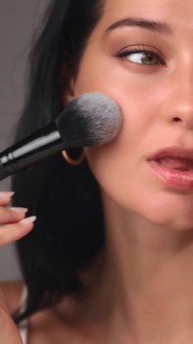 Makyaj fırçası kullanarak dış görünüşünü yumuşak, doğal makyajla geliştiren bir kadının yakın çekimi. Güzellik, kozmetik ya da makyaj için mükemmel. Zarafet ve beceri sergileyen özel promosyonlar.. 