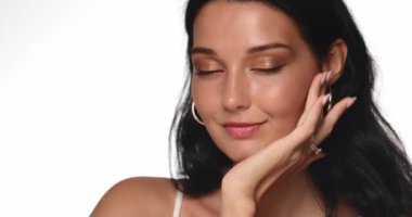 Parlak tenli, doğal makyajlı, kendine güvenen ve stüdyo ortamında usulca gülümseyen esmer bir kadının yakın çekimi. Güzellik, cilt bakımı ve makyaj ürünleri kampanyaları için mükemmel.. 