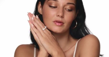 Parlak tenli ve doğal makyajlı esmer bir kadının yakın plan portresi, nazikçe ellerini çırpıyor ve yavaşça gülümsüyor. Cilt bakımı, güzellik veya yaşam tarzı tanıtım içeriği için mükemmel. 