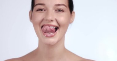 Gülümseyen bir kadının şakacı bir şekilde dilini uzatması, sağlıklı dişlerini göstermesi ve ağız hijyenini değiştirmesi. Diş hekimi reklamları, diş bakımı promosyonları ve stomatoloji kavramları için ideal.. 