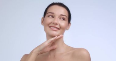 Neşeli bir kadının eli üzerinde çenesini dinlendirirken, parıldayan, kusursuz cildini ön plana çıkarırken. Lüks cilt bakımı, spa tedavisi ve güzellik ürünleri promosyonları için mükemmel.. 