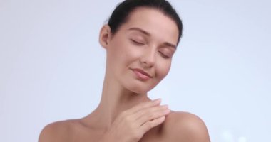 Parlak, pürüzsüz bir teni olan sakin, beyaz bir kadın gözlerini kapatır ve nazikçe boynuna dokunur. Güzellik, cilt bakımı, sağlık ve lüks yaşam tarzı promosyonları için ideal.. 