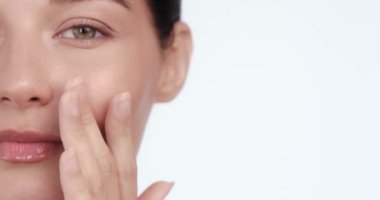 Yüzüne nazikçe dokunan neşeli bir kadının yakın plan portresi. Parlak, parlak bir ten. Lüks cilt bakımı kampanyaları, spa tedavileri ve kozmetik reklamları için mükemmel.. 